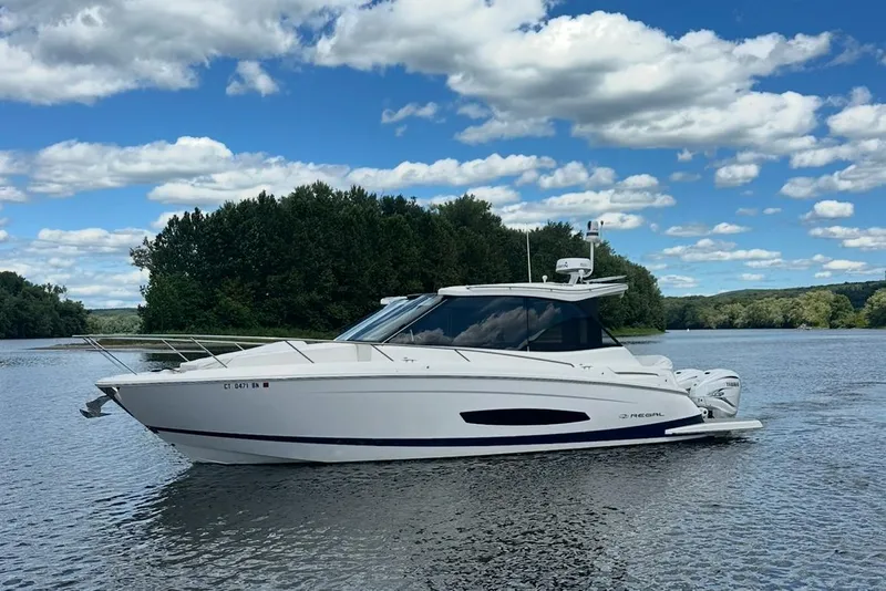 Slide: The Image of 2022 Regal 36 XO boat on a serene lake with lush green trees. - 61