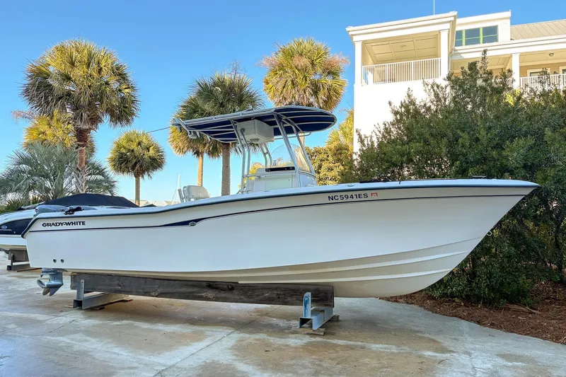 The Image of 2001 Grady-White Chase 263 boat on display, surrounded by palm trees and a modern building. - 0