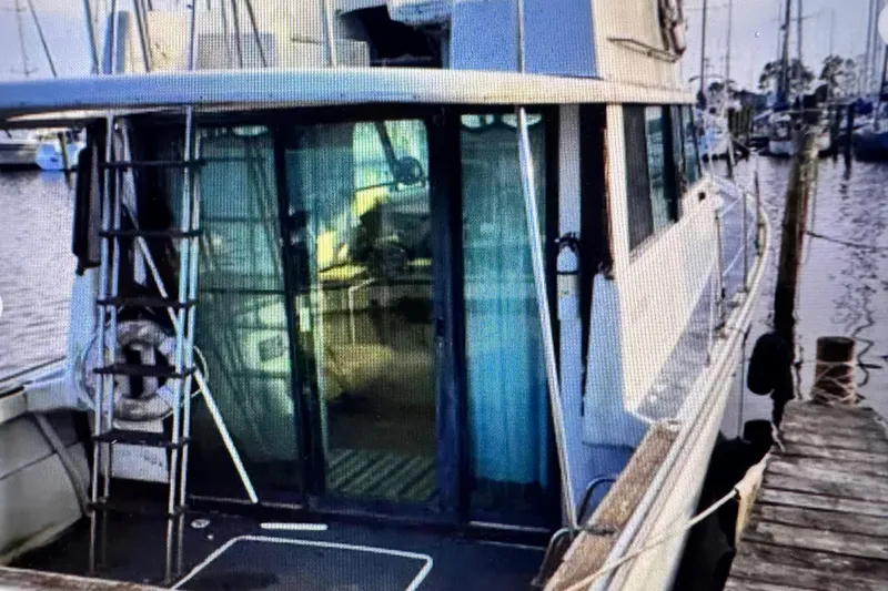 The Image of 1978 Mainship 34 Trawler docked, showcasing rear deck and glass doors. - 1