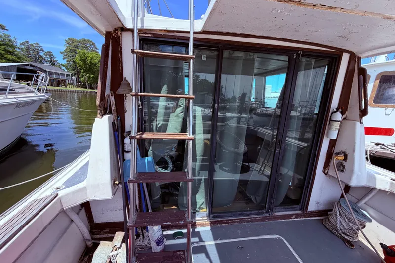 Slide: The Image of 1978 Mainship 34 Trawler with ladder and sliding glass doors at a marina. - 10