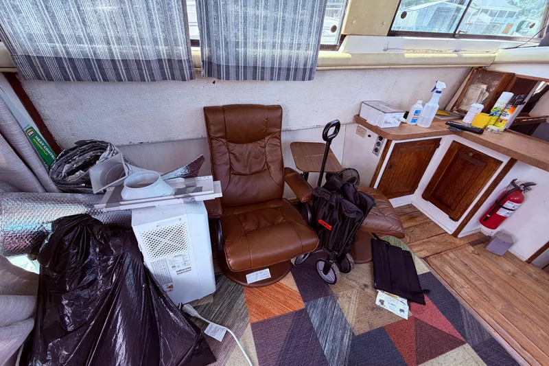 Slide: The Image of Interior of a 1978 Mainship 34 Trawler with chair, supplies, and wooden cabinets. - 17