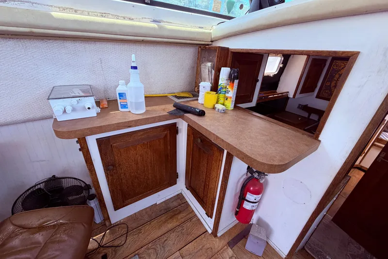 Slide: The Image of 1978 Mainship 34 Trawler interior with wooden cabinets, countertop, and cleaning supplies. - 32