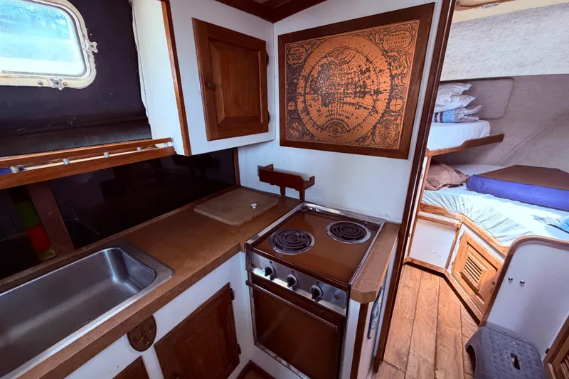 Slide: The Image of 1978 Mainship 34 Trawler interior with kitchen, stove, sink, and cozy sleeping area. - 40