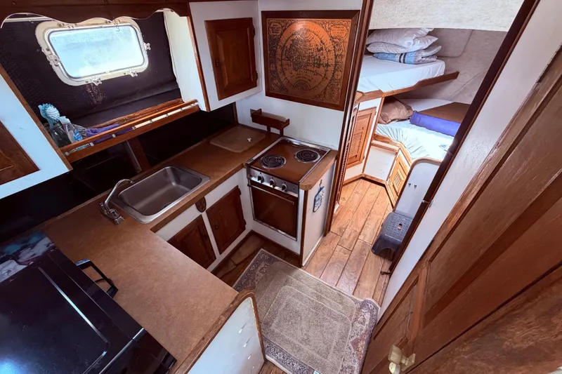 Slide: The Image of 1978 Mainship 34 Trawler interior with kitchen, stove, sink, and cozy sleeping area. - 44