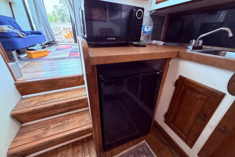 Slide: The Image of 1978 Mainship 34 Trawler interior with microwave, mini-fridge, and wooden cabinetry. - 45