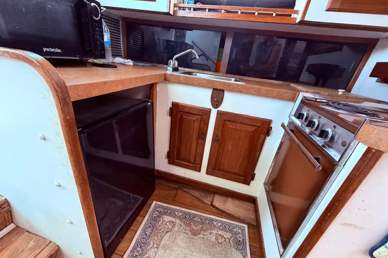 Slide: The Image of 1978 Mainship 34 Trawler kitchen with wood cabinets, stove, fridge, and microwave. - 46