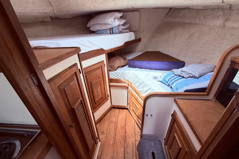 Slide: The Image of Cozy cabin interior of 1978 Mainship 34 Trawler with wooden cabinetry and bedding. - 47