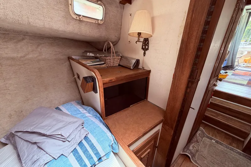 Slide: The Image of Cozy cabin interior of 1978 Mainship 34 Trawler with bed, lamp, and wooden furnishings. - 53