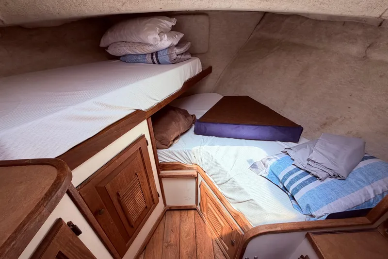 Slide: The Image of Cozy cabin interior of 1978 Mainship 34 Trawler with wooden cabinetry and bedding. - 54