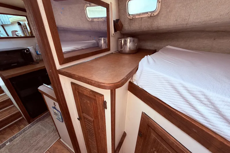 Slide: The Image of 1978 Mainship 34 Trawler interior with wooden cabinetry and cozy sleeping area. - 55
