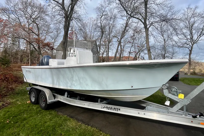 Slide: The Image of 2023 Jones Brothers 23 Cape Fisherman Lite Tackle boat on trailer in wooded area. - 2