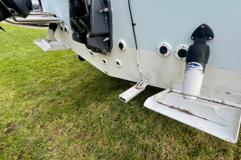 Slide: The Image of 2023 Jones Brothers 23 Cape Fisherman Lite Tackle boat with trim tabs on grassy surface. - 32