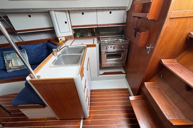 Slide: The Image of Interior of 1987 O'Day 322 sailboat with kitchen, sink, stove, and wooden cabinetry. - 16
