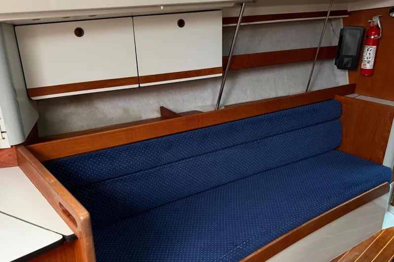Slide: The Image of 1987 O'Day 322 sailboat interior with blue cushioned seating and wooden cabinetry. - 22