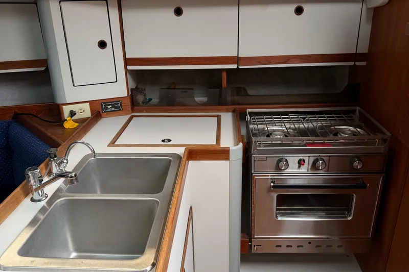 Slide: The Image of 1987 O'Day 322 yacht kitchen with stainless steel sink and stove, wooden cabinetry. - 27