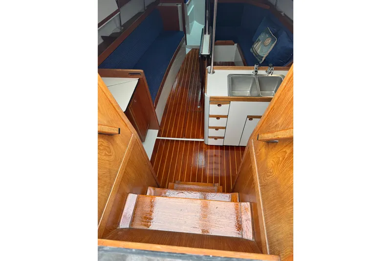 Slide: The Image of 1987 O'Day 322 yacht interior with wooden flooring and compact kitchen area. - 7