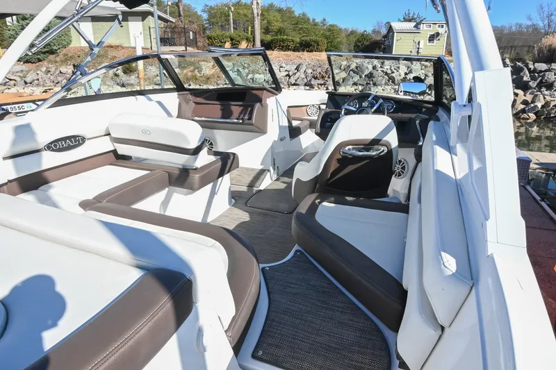 Slide: The Image of 2023 Cobalt CS22 boat interior with white and brown seating, docked by rocky shore. - 10