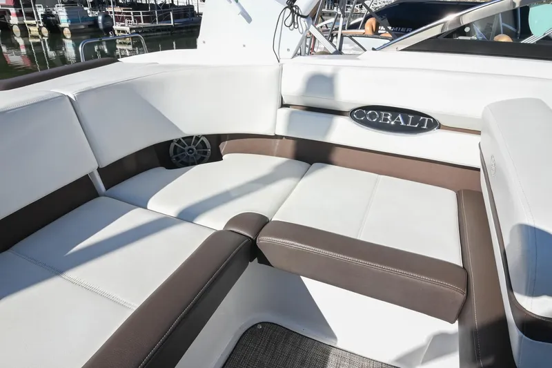 Slide: The Image of 2023 Cobalt CS22 boat interior with white and brown seating at a marina. - 15