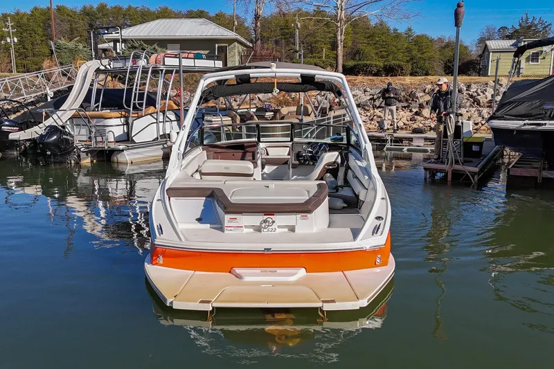 Slide: The Image of 2023 Cobalt CS22 boat docked at marina, surrounded by other boats and scenic background. - 2