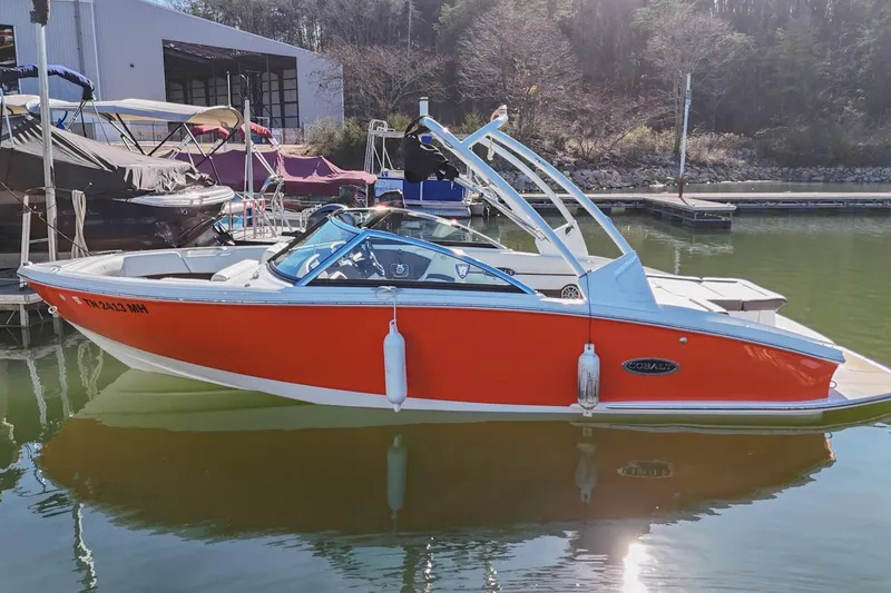 Slide: The Image of 2023 Cobalt CS22 boat in vibrant orange, docked at a marina. - 4