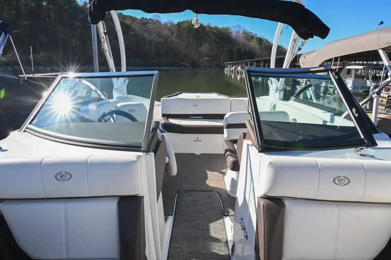 Slide: The Image of 2023 Cobalt CS22 boat interior with white seating and clear windshields on a sunny day. - 8