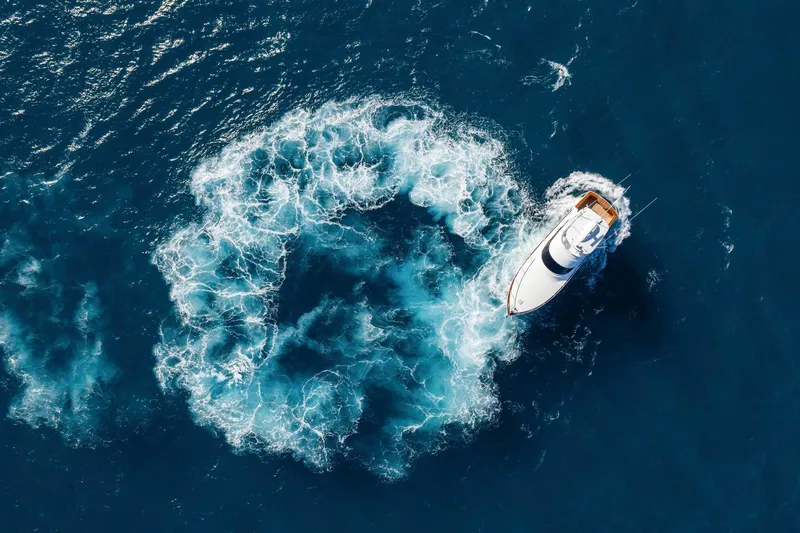 Slide: The Image of Aerial view of 2025 Viking 58 Convertible yacht creating a circular wake in deep blue ocean. - 10