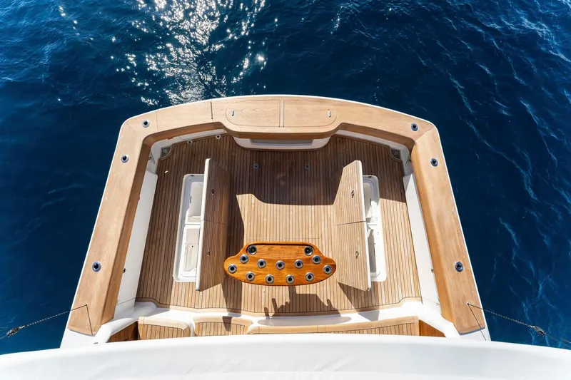 Slide: The Image of 2025 Viking 58 Convertible yacht deck with wooden finish, overlooking deep blue ocean. - 32