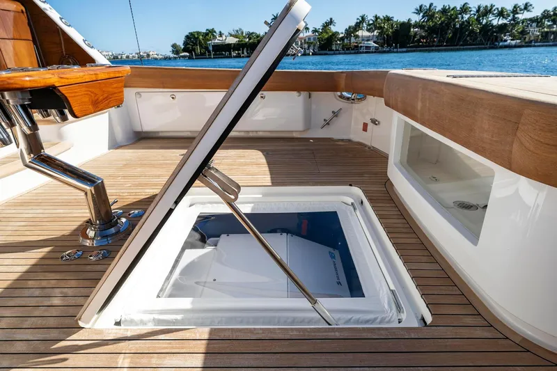 Slide: The Image of 2025 Viking 58 Convertible yacht deck with open hatch, showcasing luxurious wood finish. - 35