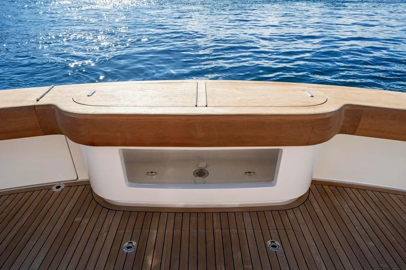 Slide: The Image of 2025 Viking 58 Convertible yacht deck with wooden finish, overlooking serene blue waters. - 36