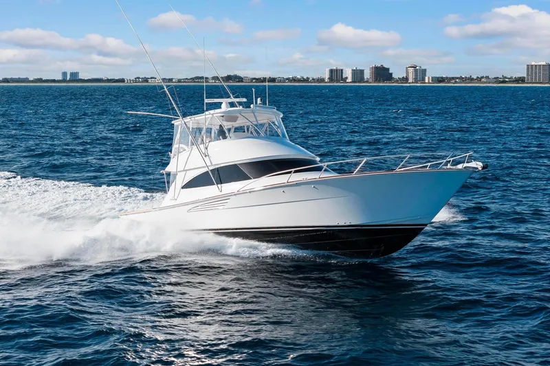 Slide: The Image of 2025 Viking 58 Convertible yacht cruising on open water, city skyline in background. - 6