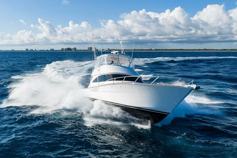 Slide: The Image of 2025 Viking 58 Convertible yacht cruising on open ocean with city skyline in background. - 9