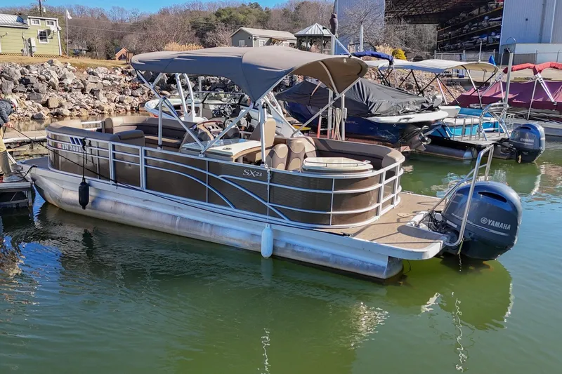 Slide: The Image of 2021 Bennington SX 23 Entertainment pontoon boat docked with Yamaha outboard motor. - 2