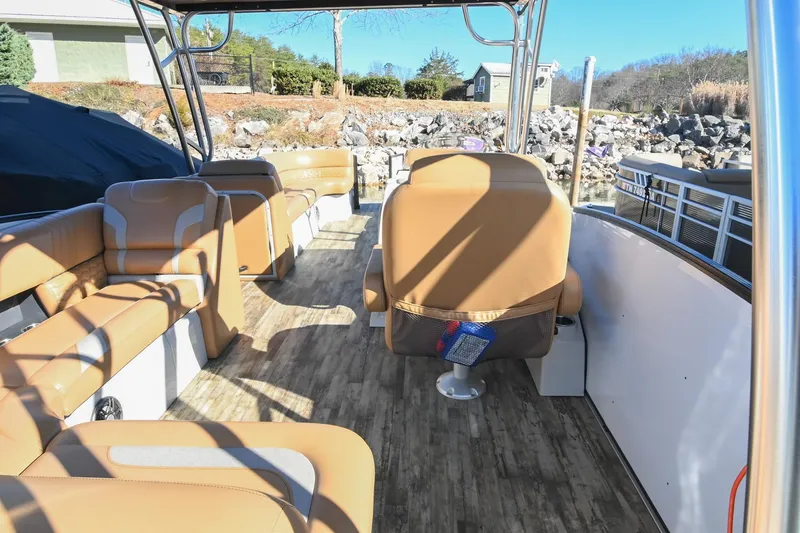 Slide: The Image of 2023 Crest Caribbean LX 250 pontoon boat interior with tan seating and wood flooring. - 13