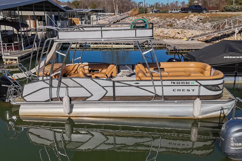 Slide: The Image of 2023 Crest Caribbean LX 250 pontoon boat docked at a marina. - 2