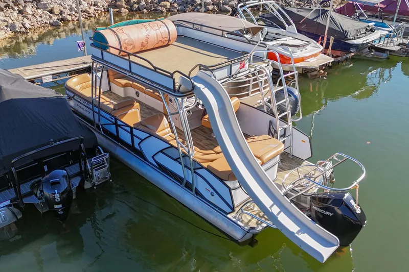 Slide: The Image of 2023 Crest Caribbean LX 250 pontoon boat with slide, docked in a marina. - 3