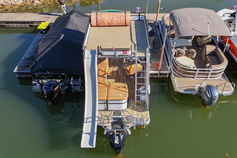 Slide: The Image of 2023 Crest Caribbean LX 250 pontoon boat docked, featuring spacious seating and a slide. - 4