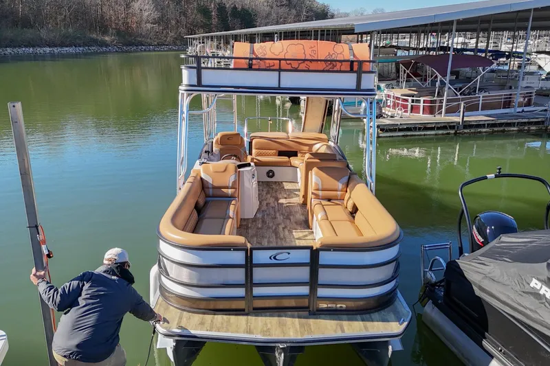 Slide: The Image of 2023 Crest Caribbean LX 250 pontoon boat docked on a calm lake. - 6