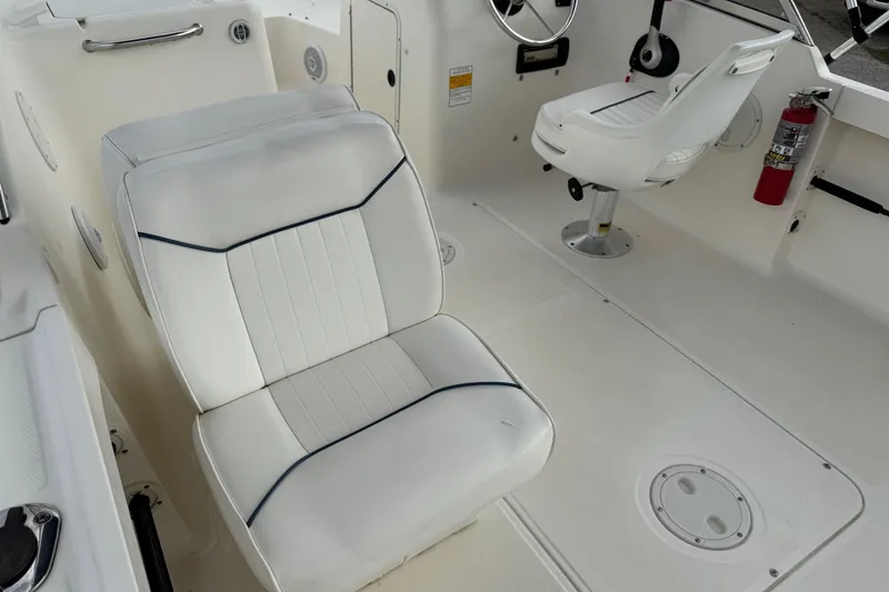Slide: The Image of Interior of 2000 Sea Hunt Escape 200 boat with white seating and steering area. - 4