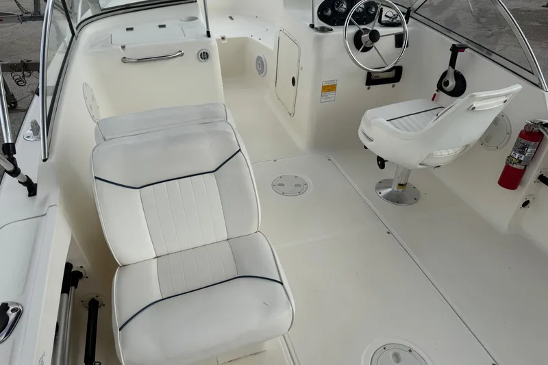 Slide: The Image of Interior of a 2000 Sea Hunt Escape 200 boat with white seating and steering wheel. - 7