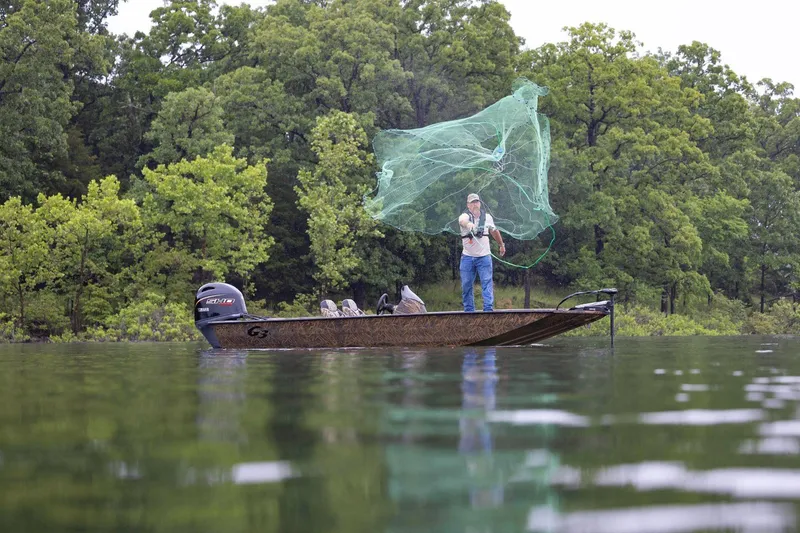Slide: The Image of Man casting net from 2026 G3 Sportsman 1710 boat on a serene lake. - 3