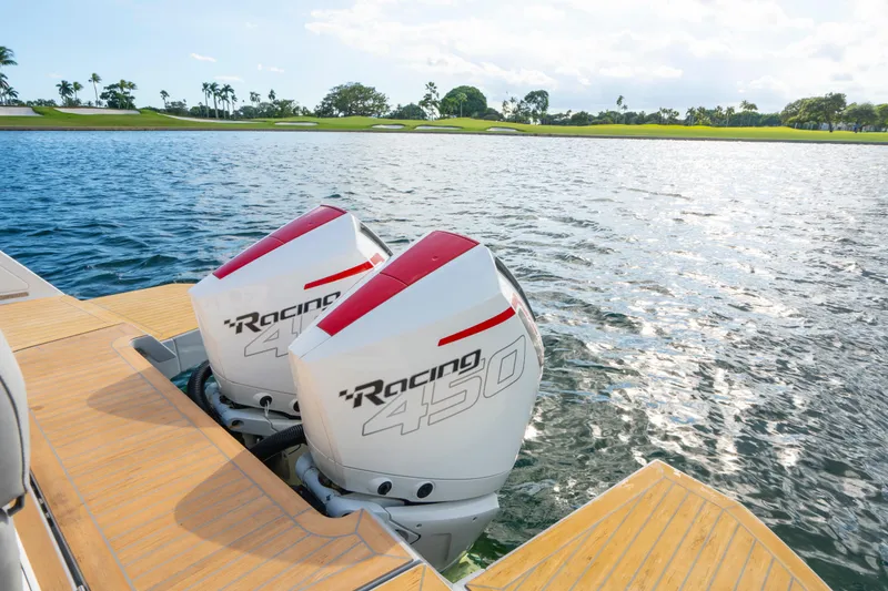 Slide: The Image of Twin Racing 450 engines on 2021 Pardo Yachts 38, docked by a scenic lake. - 10