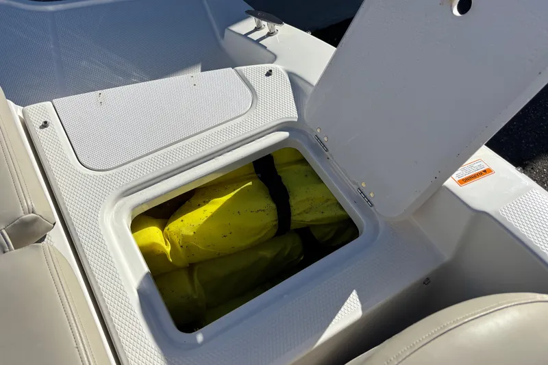 Slide: The Image of Open storage compartment in 2015 Chaparral 19 H2O Ski & Fish boat, containing yellow life jacket. - 19