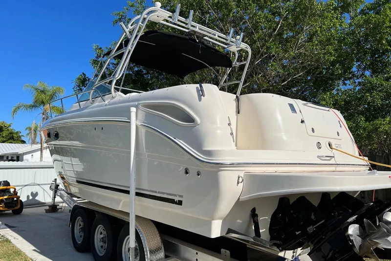 Slide: The Image of 2007 Sea Ray 270 Amberjack boat on trailer, surrounded by trees and clear blue sky. - 2