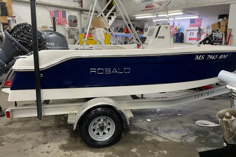 The Image of 2019 Robalo R160 Center Console boat on trailer in garage setting. - 0