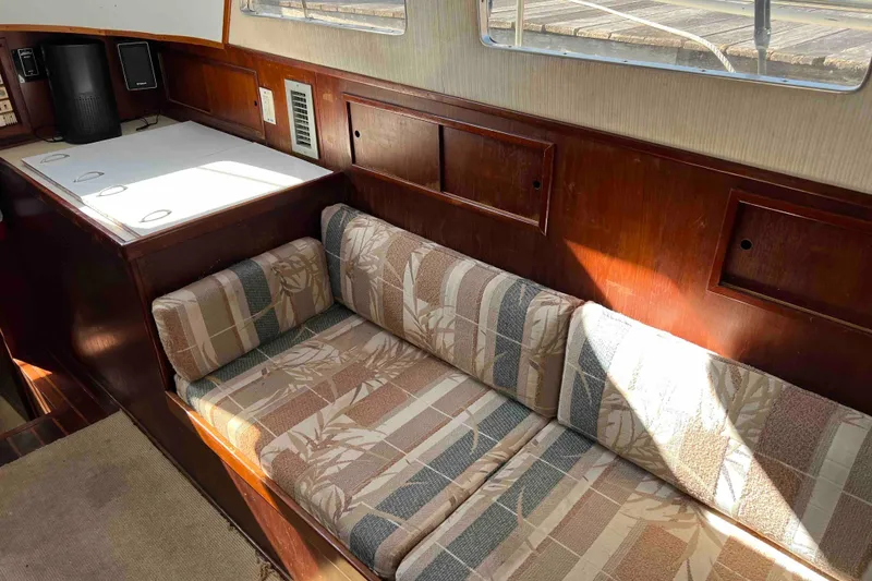 Slide: The Image of Interior of 1980 Wellington 44 Cutter Center Cockpit with cushioned seating and wooden paneling. - 16