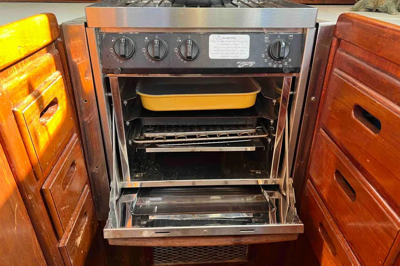 Slide: The Image of 1980 Wellington 44 Cutter Center Cockpit kitchen with open oven and yellow baking dish. - 26