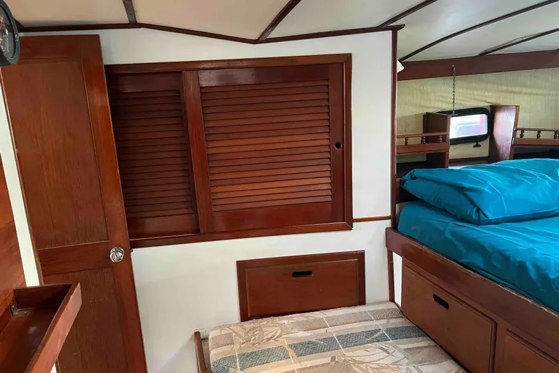 Slide: The Image of Interior of 1980 Wellington 44 Cutter Center Cockpit with wooden cabinetry and blue bedding. - 38