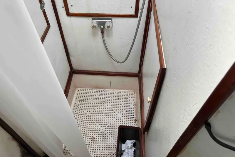 Slide: The Image of Shower area in 1980 Wellington 44 Cutter Center Cockpit boat, featuring wooden trim and white curtain. - 44