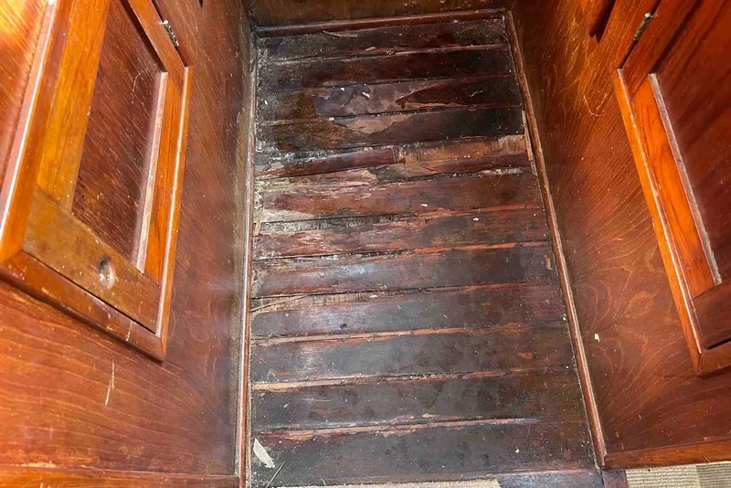 Slide: The Image of Wooden interior of 1980 Wellington 44 Cutter Center Cockpit, featuring aged flooring and cabinetry. - 48