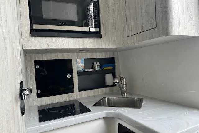 Slide: The Image of Modern kitchenette in 2022 Regulator 41 boat with sink, stove, and microwave. - 21